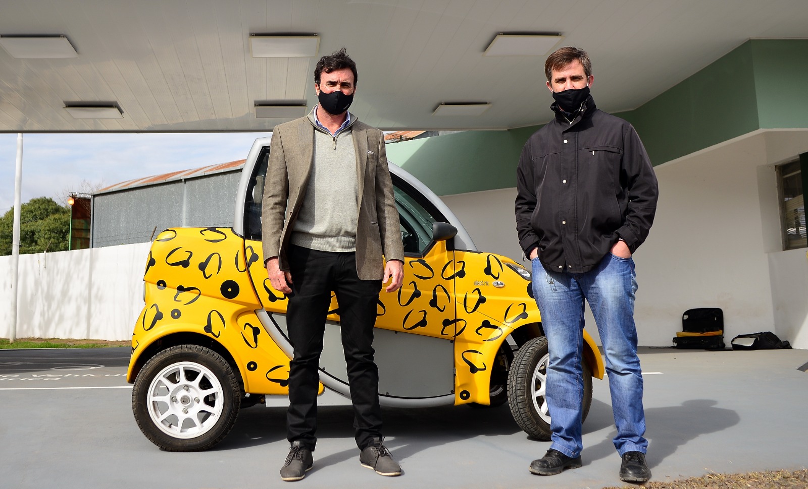 Dos personas junto a un vehículo eléctrico amarillo